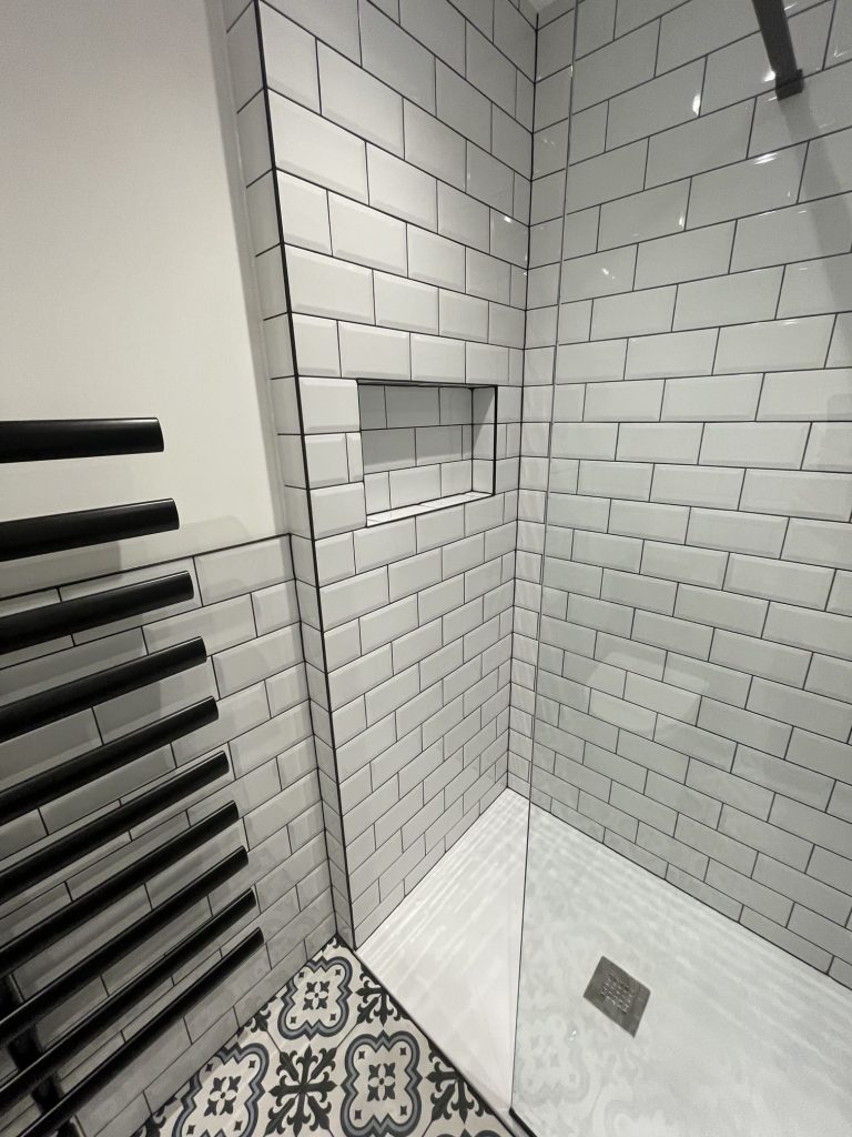 Professional white metro tiling with dark grout and built-in shower niche – Tiling specialists Reading.